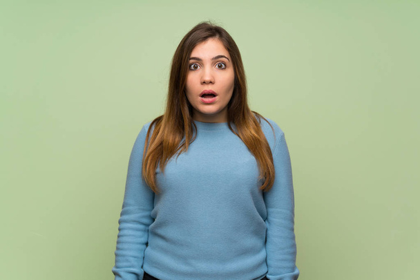 Chica joven sobre pared verde con expresión facial sorpresa
 - Foto, Imagen