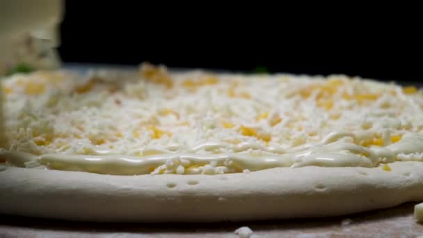 Közelről a kéz a főzés kesztyű hozzá majonéz mártással a palackból a friss pizza sütés előtt, az élelmiszer-koncepció. Keret. Cook szorító fehér mártással a pizza. - Felvétel, videó