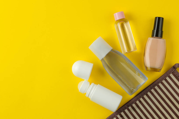 A set of cosmetics and personal care products for travel in a cosmetic bag on a bright yellow background. top view. travel cosmetics - Photo, Image