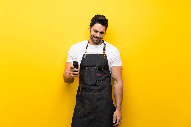 Young hairdresser man over isolated yellow background - 写真・画像