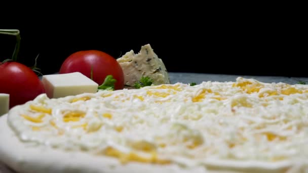焼く前に新鮮なピザ、食品のコンセプトのためにクローズアップ。フレーム。チーズとマヨネーズソースとトマトの新鮮なピザと黒い背景に分離されたチーズの作品. - 映像、動画