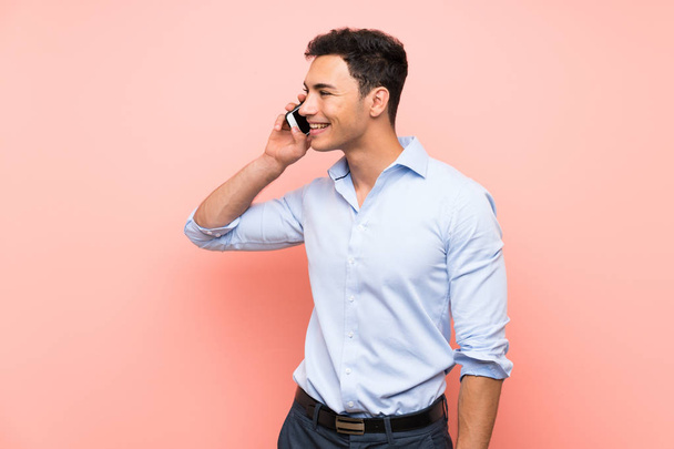 Красивый мужчина на розовом фоне поддерживает разговор с мобильным телефоном
 - Фото, изображение