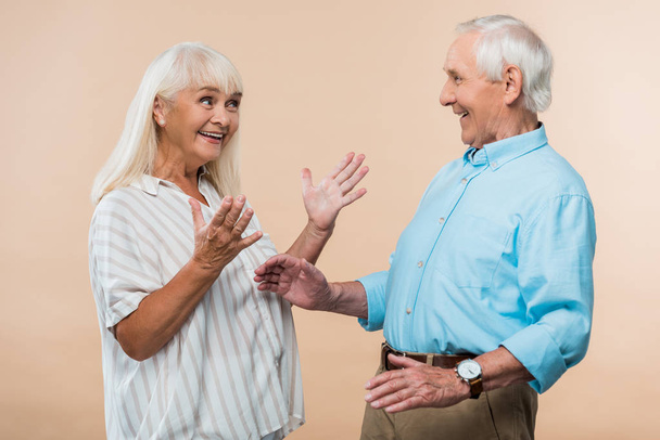 mutlu yaşlı karısı bej izole kocası bakarken gesturing  - Fotoğraf, Görsel