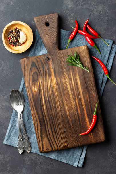 Food cooking concept. Vintage wooden kitchen board, cutlery and red pepper over napkin on dark stone background. Top view. - Φωτογραφία, εικόνα