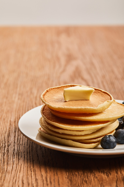 selective focus of pancakes with butter on plate on wooden surface - Valokuva, kuva