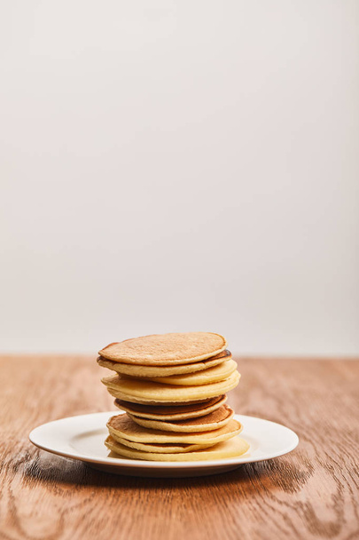 chutné palačinky k snídani na bílém plechu na dřevěné ploše izolované na šedé - Fotografie, Obrázek