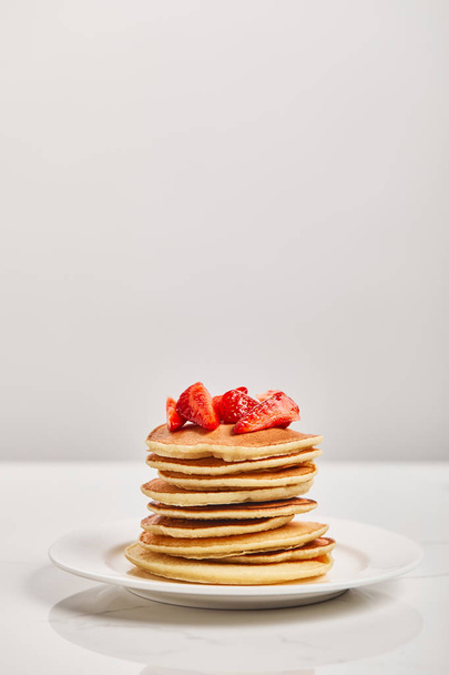 pancakes for breakfast with strawberries on white plate isolated on grey - Фото, изображение