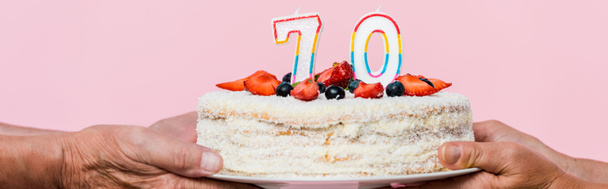 panoramic shot of retired couple holding birthday cake isolated on pink  - Фото, зображення