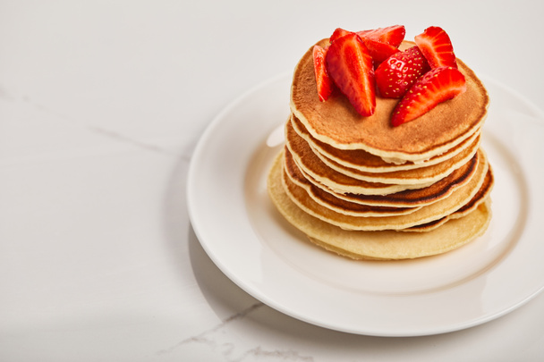 tasty pancakes for breakfast with strawberries on white plate on textured surface - Фото, изображение