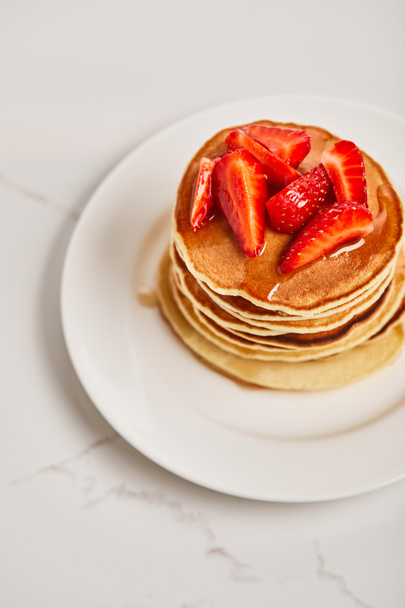 tasty pancakes with strawberries and syrup on white plate on textured surface - Photo, Image