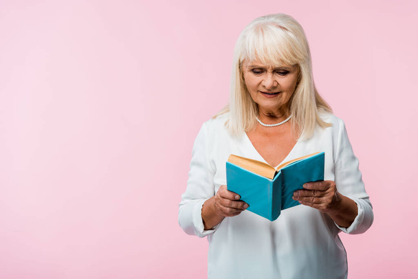 donna anziana con capelli grigi libro di lettura isolato su rosa
  - Foto, immagini