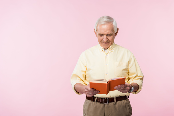 happy retired man reading book and smiling on pink  - Foto, immagini