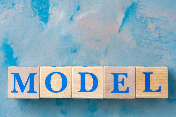 Wooden cubes with word MODEL on blue table. - Foto, Bild