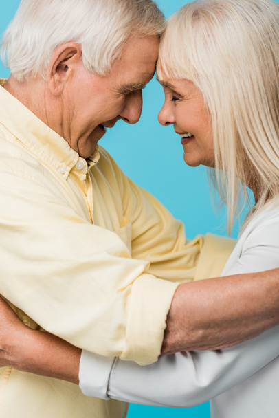 side view of happy retired couple with closed eyes smiling isolated on blue  - Фото, изображение
