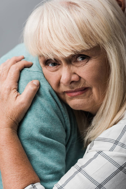 close up of husband hugging sad retired wife with grey hair isolated on grey  - Φωτογραφία, εικόνα