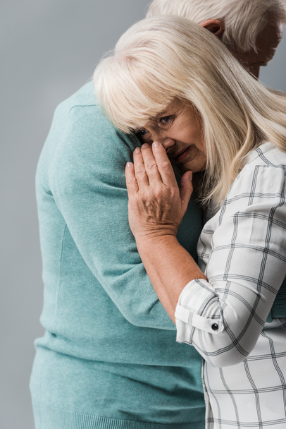 przycięte widok męża przytulanie emerytowana żona pokrywająca twarz podczas płacz na szaro  - Zdjęcie, obraz