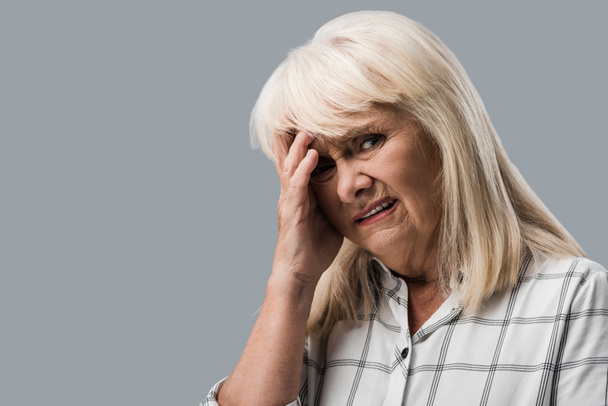 tired and upset retired woman touching head and looking at camera isolated on grey  - Фото, изображение