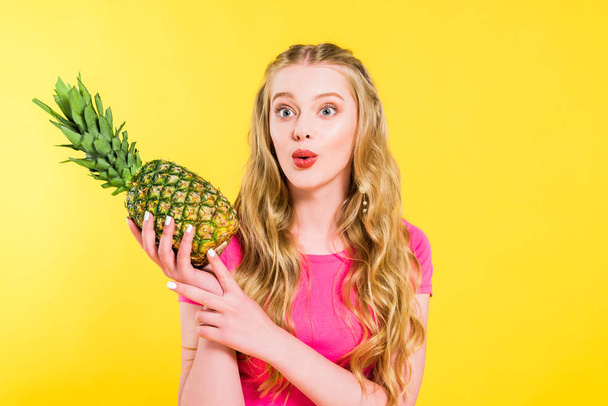 beautiful surprised girl holding pineapple Isolated On yellow - Photo, Image