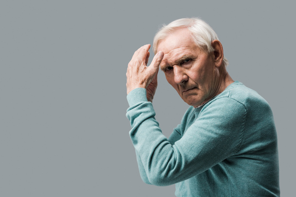 exhausted and upset retired man gesturing and looking at camera isolated on grey  - Foto, afbeelding