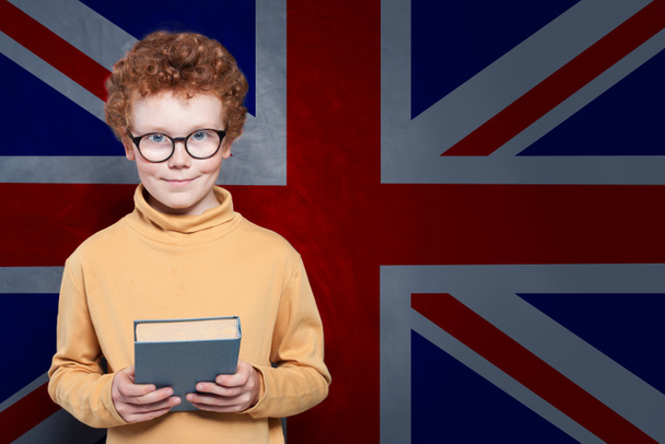 Ingiltere bayrağı arka planda akıllı çocuk tutan kitap - Fotoğraf, Görsel