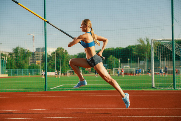 Female high jumper training at the stadium in sunny day - Photo, Image