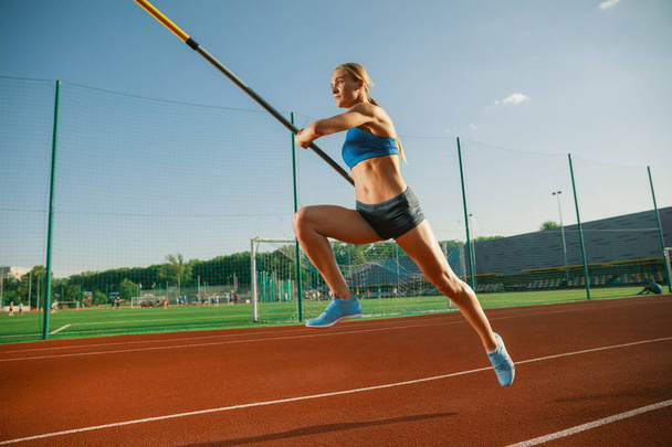 Female high jumper training at the stadium in sunny day - Foto, afbeelding