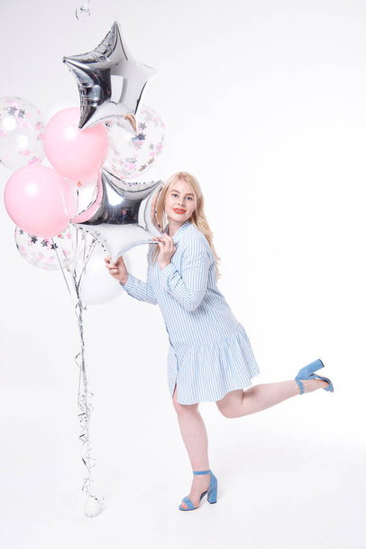 Full length portrait of a joyful young woman, rejoices and celebrates on a white background with multi-colored balloons. - Photo, Image