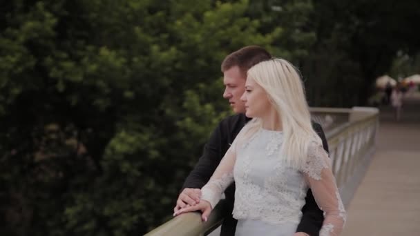 Boldog pár szerelmes állva a vashídon a városi parkban, és átölelve. - Felvétel, videó