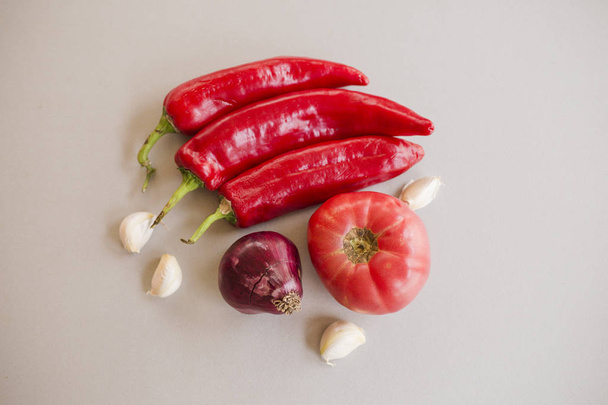 red chili peppers and garlic cloves with tomato and onion on light background  - Valokuva, kuva