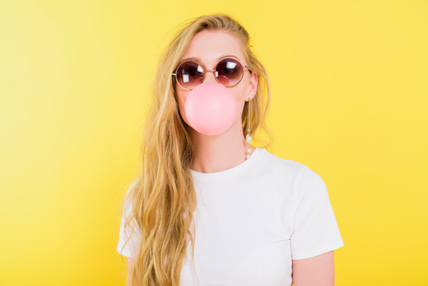 piękna dziewczyna w okularów dmuchanie guma Bubble izolowane na żółto - Zdjęcie, obraz