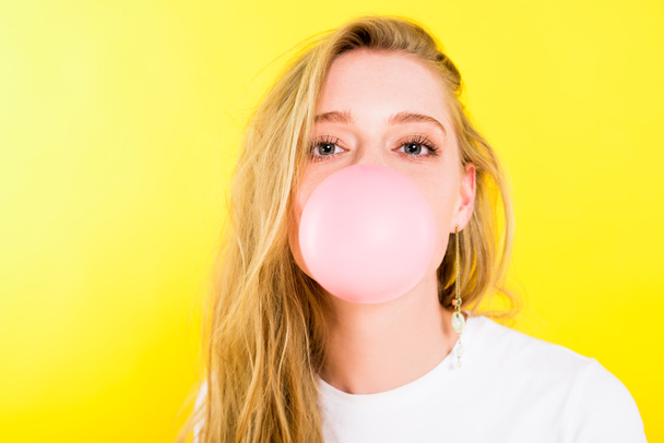 beautiful girl blowing bubble gum Isolated On yellow - Photo, Image