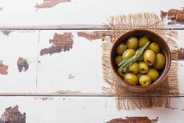grüne Oliven in hölzernen Schalen auf einem Holztisch. Draufsicht mit Platz für Text. - Foto, Bild