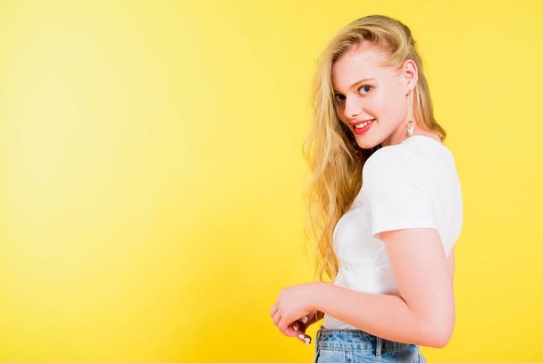 beautiful smiling blonde young woman looking at camera On yellow - Zdjęcie, obraz