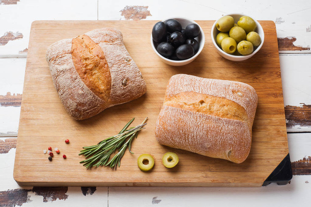 Italian ciabatta bread with olives and rosemary on a wooden Board. - Фото, зображення
