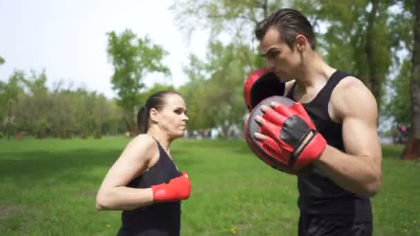 4. Man boxer training woman with  boxing paws. City park outdoor sport team - Footage, Video