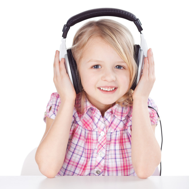 Girl Listening To Music On Headphones While Sitting At Table - Foto, Imagen