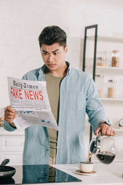 shocked asian man reading fake news newspaper while pouring coffee in cup  - Photo, Image