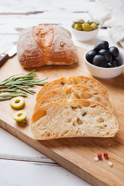 Pan de ciabatta italiano con aceitunas y romero en una tabla de madera
. - Foto, imagen