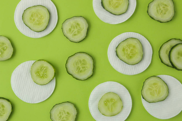 slices of fresh cucumber and cotton sponge on a bright green background. cucumber cosmetics concept. skin care. tonic cucumber extract - Foto, immagini