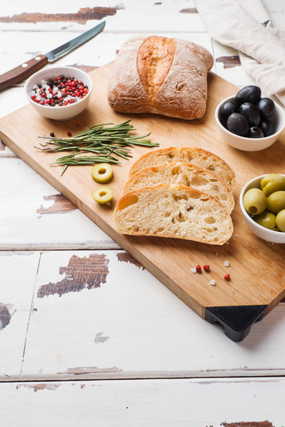 Włoski chleb ciabatta z oliwkami i rozmarynem na drewnianej płycie. Kopiuj przestrzeń - Zdjęcie, obraz