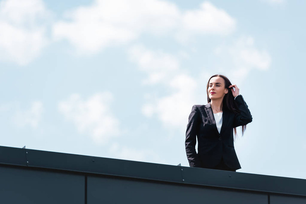 attractive businesswoman standing on rooftop, smiling an looking away - 写真・画像