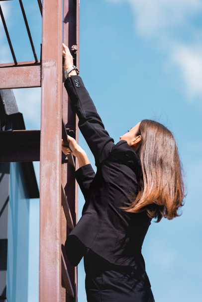 молодая бизнесвумен в формальной одежде поднимается по лестнице на крышу
 - Фото, изображение