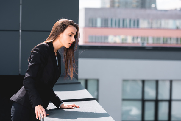 young businesswoman, suffering from acrophobia, looking down rooftop - Photo, Image