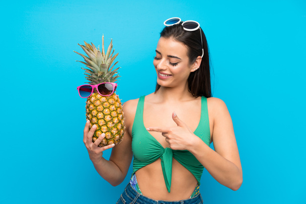 Young woman in swimsuit in summer holidays holding a pineapple with sunglasses - Foto, Imagem