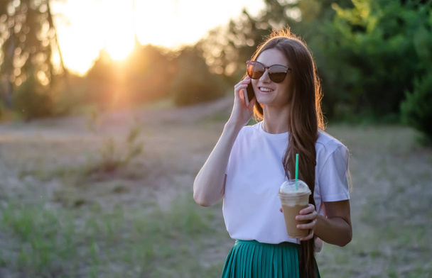 Молода дівчина з кавовим коктейлем. У сонячних окулярах. Літнє зображення
. - Фото, зображення