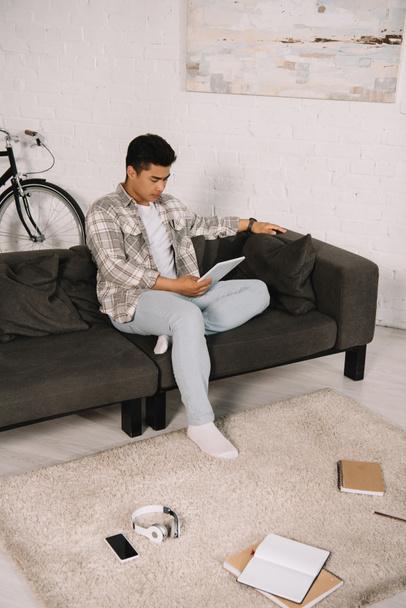 young asian man sitting on sofa at home and using digital tablet - Fotoğraf, Görsel