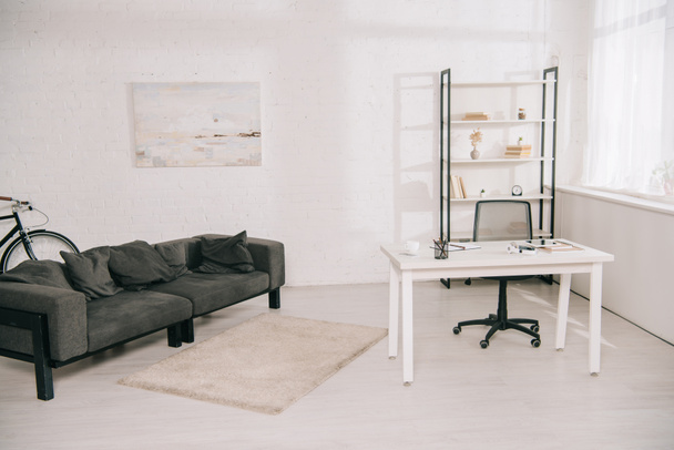 amplio salón con sofá gris, mesa blanca y estante con libros
 - Foto, imagen