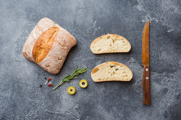 Italian ciabatta bread with olives and rosemary on a Dark concrete background. Copy space - 写真・画像