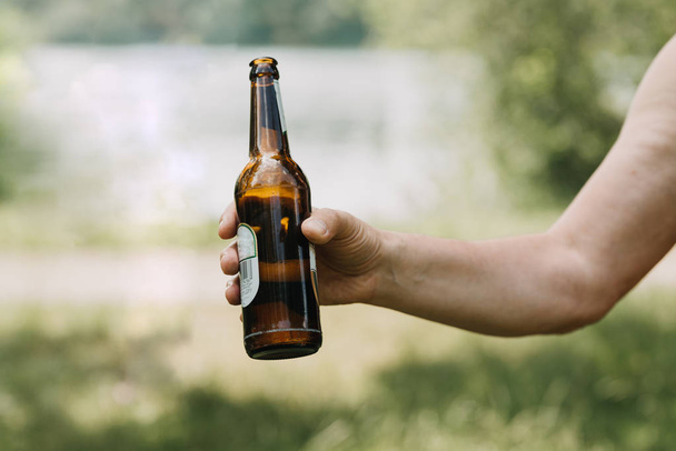 hand of man holding a bottle of beer in forest outdoor - Foto, Bild