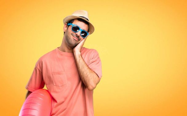 Człowiek z kapeluszem i okulary przeciwsłoneczne na wakacjach co gest snu. Urocza i słodka ekspresja na pomarańczowym tle - Zdjęcie, obraz